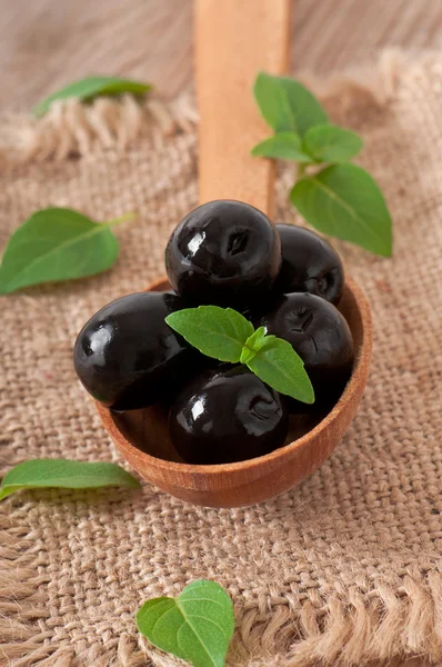 Черные оливки на деревянном столе — стоковое фото
