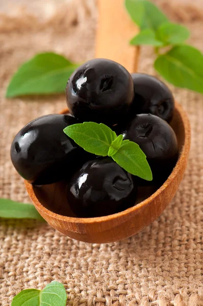 Svarta oliver på ett träbord — Stockfoto