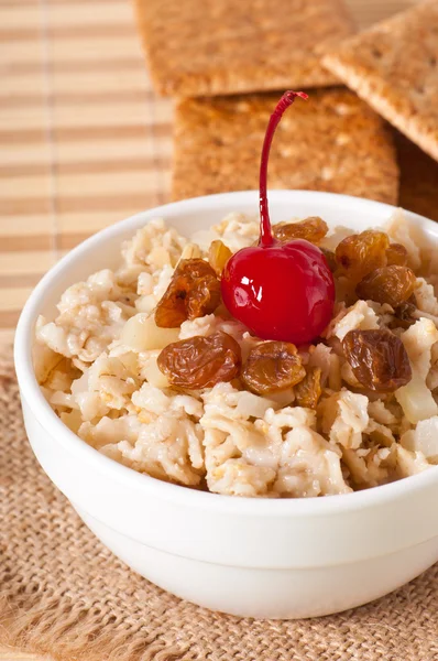 Oatmeal with raisins and cherries in a white bowl — Stock Photo, Image