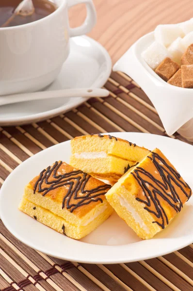 Slice of sponge cake with tea and sugar — Stock Photo, Image