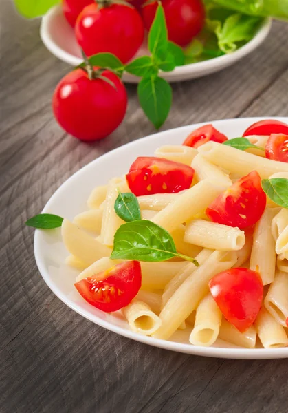 Ensalada de pasta con tomates cherry y hojas de albahaca fresca — Foto de Stock