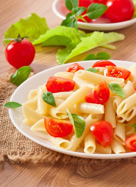 Salada de macarrão com tomate cereja e folhas de manjericão fresco — Fotografia de Stock