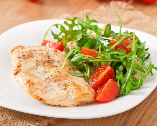 Filete a la parrilla de pollo y una ensalada de rúcula y tomate —  Fotos de Stock