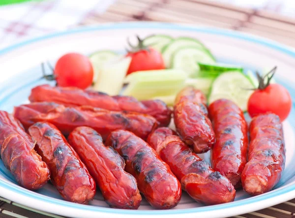 Grilled sausages on the grill and a salad of fresh vegetables — Stock fotografie