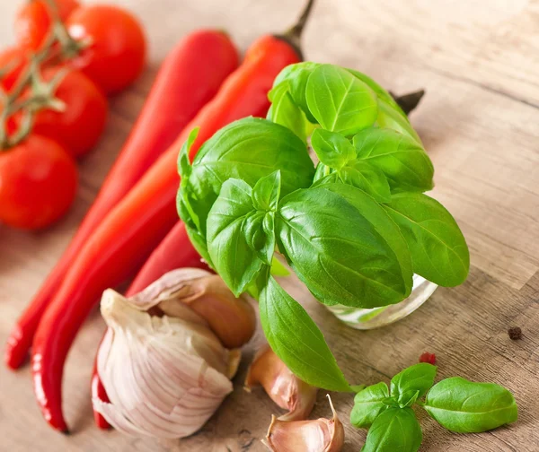 Peperoncini rossi, pomodori, aglio e basilico su fondo di legno — Foto Stock