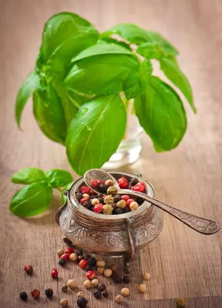 Mixture of pepper peas in an old bowl and basil leaves — Stock Photo, Image