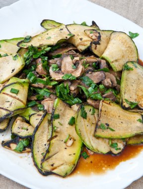 Slices of zucchini and mushrooms grilled in a sauce clipart