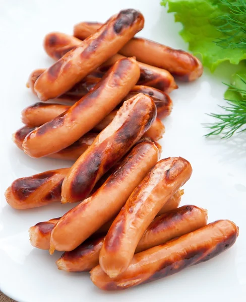 Grilled sausages on the grill and a salad Royalty Free Stock Photos