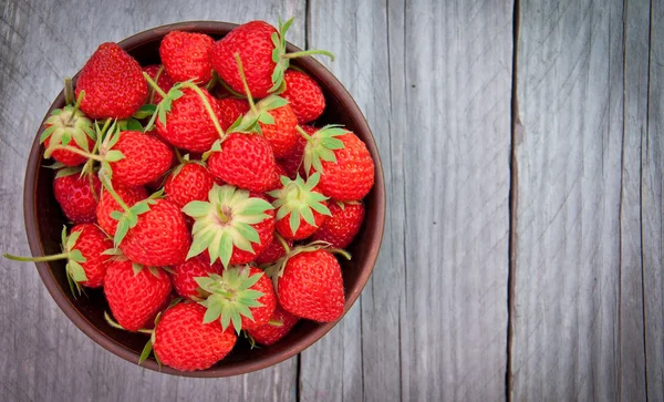 Erdbeeren in Keramikschale auf altem Holzgrund — Stockfoto