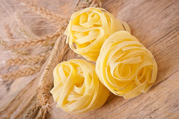 Pasta and wheat ears on the wooden table — Stock Photo, Image