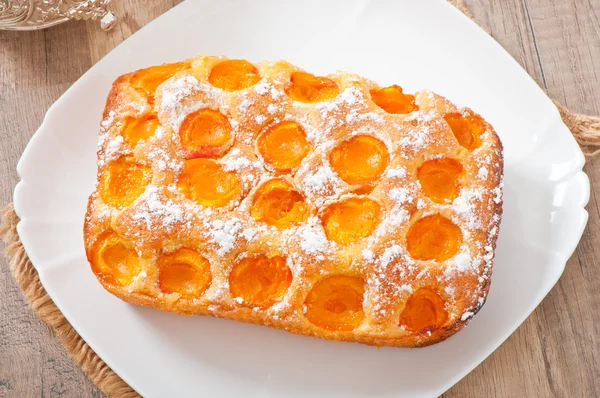 Sponge cake with apricots sprinkled with powdered sugar — Stock Photo, Image