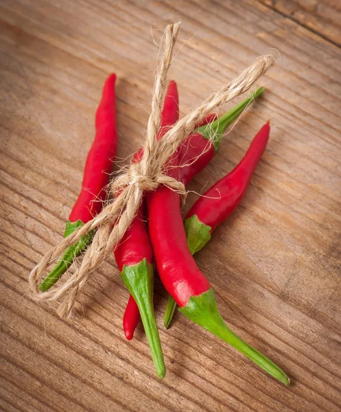 Red hot chili papričky svázané provazem izolovaných na dřevěné pozadí — Stock fotografie