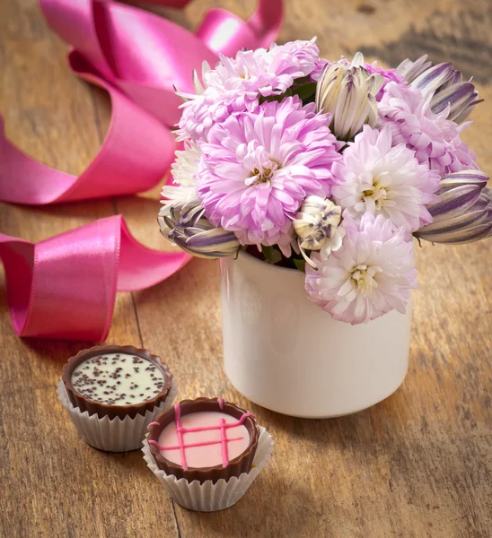Hermoso ramo de flores de aster y chocolates en la mesa de madera — Foto de Stock