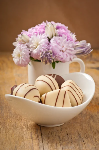 Beau bouquet de fleurs aster et chocolats sur table en bois — Photo