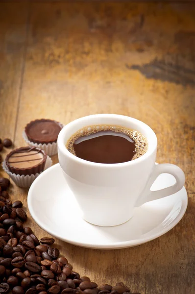 Tasse de café et bonbons au chocolat sur une vieille table en bois — Photo