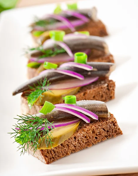 Sandwiches of rye bread with herring, onions and herbs. — Stock Photo, Image