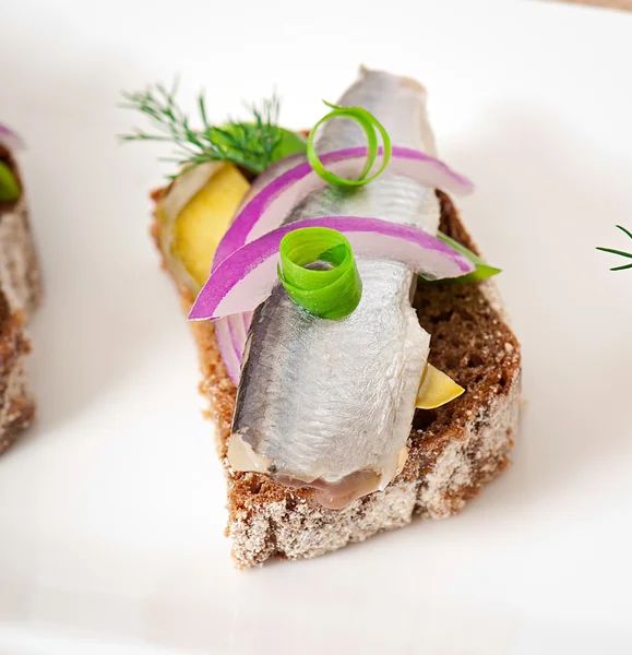 Сэндвичи из ржаного хлеба с сельдью, луком и травами . — стоковое фото