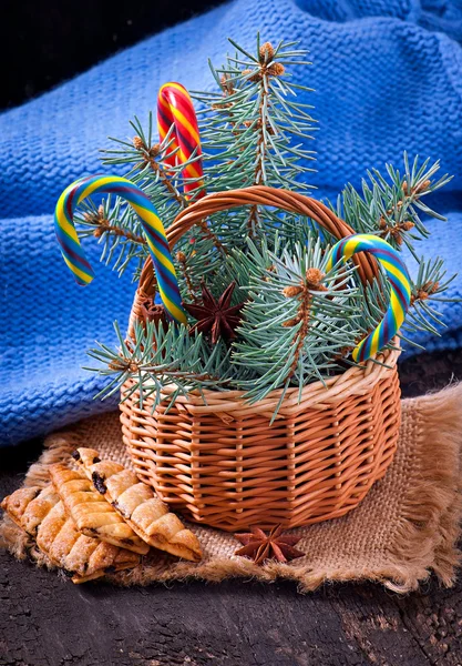 Weihnachtsschmuck und Tannenzweige im Korb auf altem Holzgrund — Stockfoto