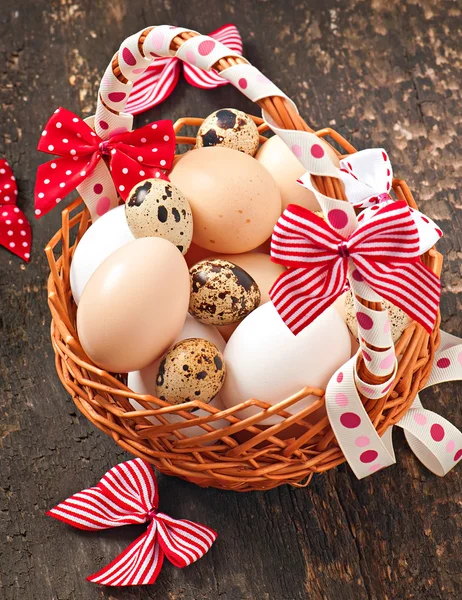 Пасхальные яйца и корзина на деревянном фоне — стоковое фото