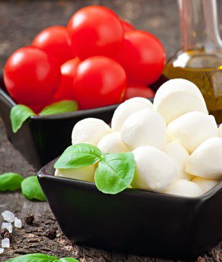 Mozzarella peyniri, domates ve taze fesleğen yaprakları üzerinde ahşap arka plan