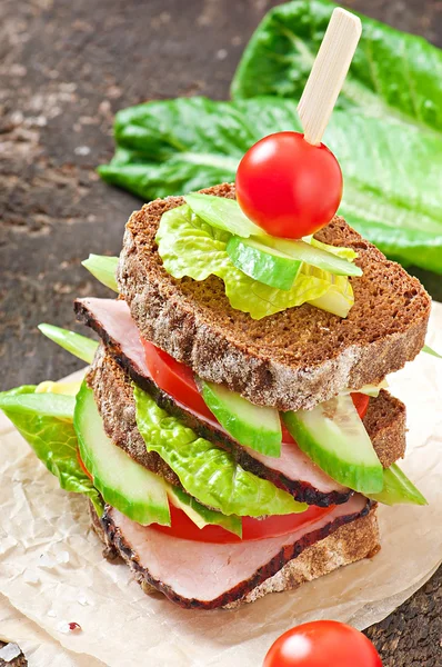 Sandwich met ham en vers fruit op een houten achtergrond — Stockfoto