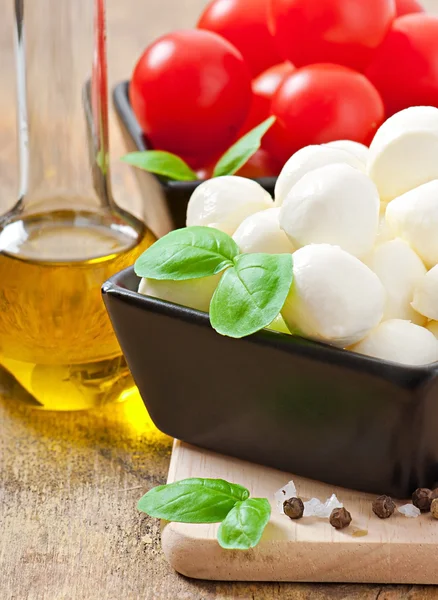 Mozzarella, tomatoes and fresh basil leaves on wooden background — Stock Photo, Image