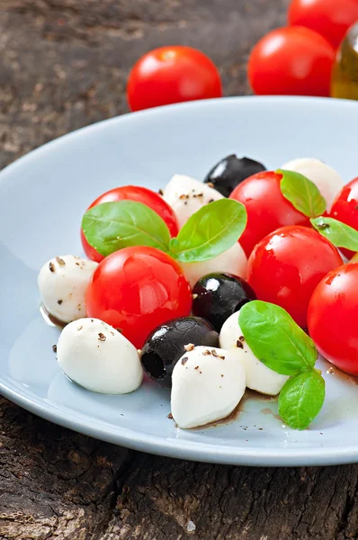 Fresh salad with cherry tomatoes, basil, mozzarella and black olives. — Stock Photo, Image