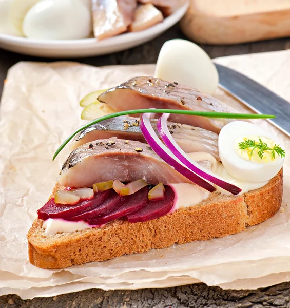 Sandwich van roggebrood met haring, bieten, uien en ei — Stockfoto