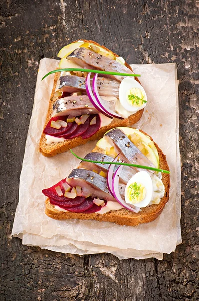 Sandwich van roggebrood met haring, bieten, uien en ei — Stockfoto