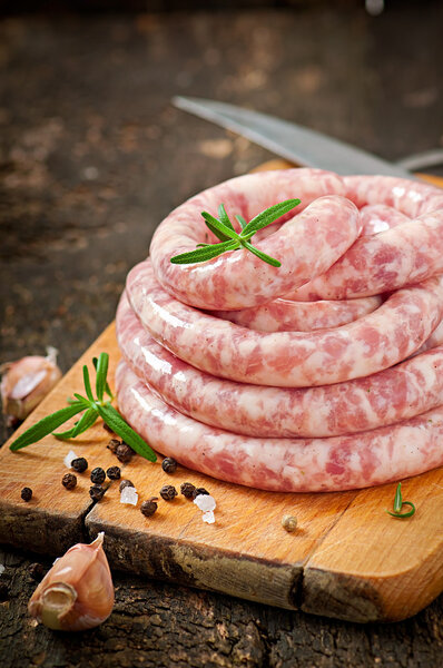 Fresh raw sausage on the old wooden background