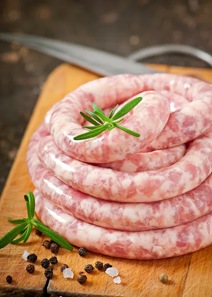 Saucisse crue fraîche sur le vieux fond en bois — Photo