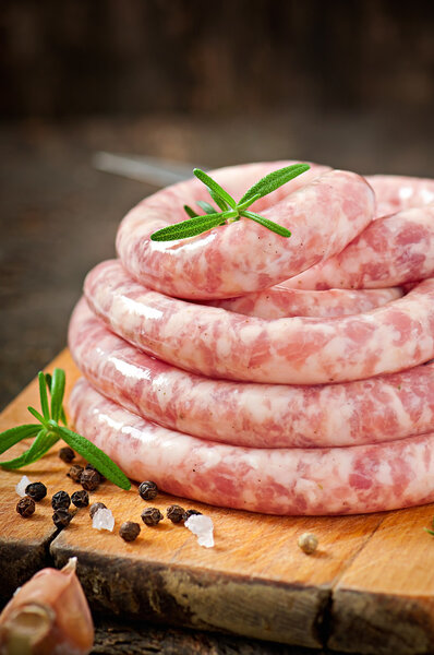 Fresh raw sausage on the old wooden background