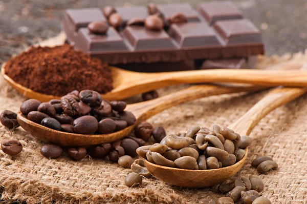 Green, roasted and ground coffee in wooden spoons — Stock Photo, Image