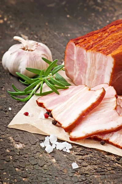 Slices smoked bacon on the old wooden background — Stock Photo, Image