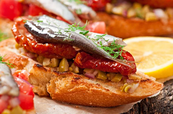 Crostini with anchovies, olives and sun-dried tomatoes — Stock Photo, Image