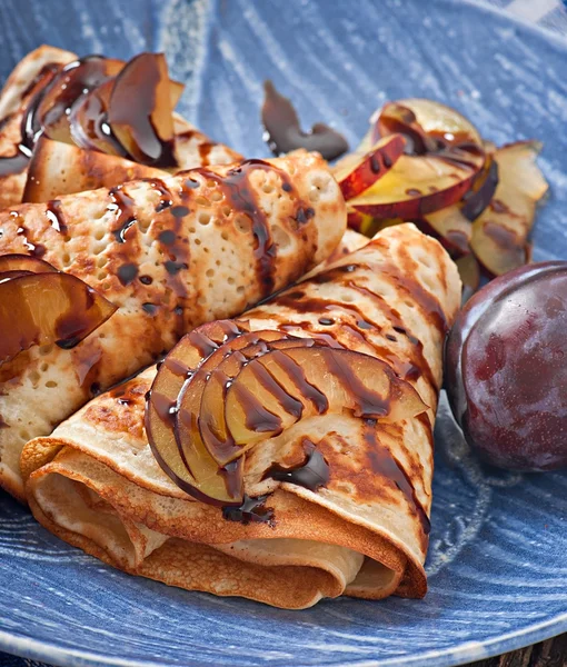 Pancakes with chocolate syrup and plums — Stock Photo, Image