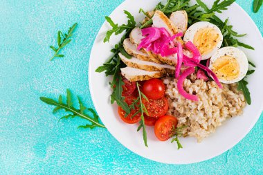 Taze salata. Yulaf ezmeli kahvaltı kasesi, tavuk fileto, domates, kırmızı soğan ve haşlanmış yumurta. Sağlıklı yiyecekler. Vejetaryen Buda kasesi. Üst manzara, düz uzanma