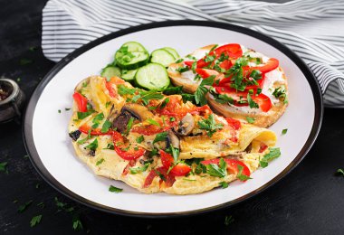 Mantarlı omlet, paprika, domates ve beyaz tabakta krem peynirli sandviç. Frittata - İtalyan omleti.