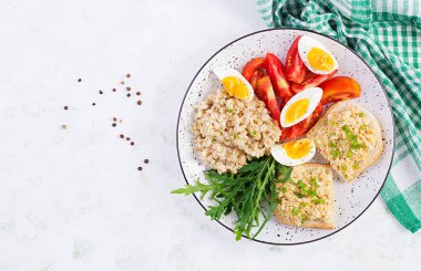Taze salata. Yulaf ezmeli kahvaltı kasesi tavuklu sandviç, domates ve haşlanmış yumurta. Sağlıklı yiyecekler. Üst manzara, düz uzanma