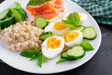 Kahvaltı yulaf lapası haşlanmış yumurta, somon sandviçi ve salatalık salatası. Sağlıklı yiyecekler. Öğle yemeği..