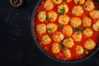Koyu arkaplanda tavada domates soslu köfte. Üst manzara, düz uzanma.