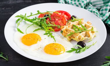 Kabaklı kahvaltı, kızarmış yumurta, domates, siyah zeytin ve beyaz arka planda roka. Aperatifler, aperatifler, brunch. Sağlıklı vejetaryen yemekleri.