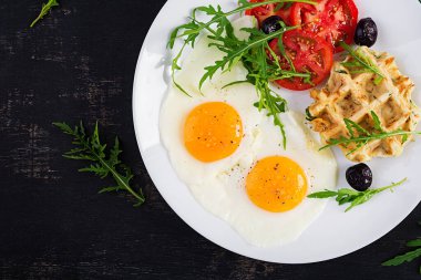 Kabaklı kahvaltı, kızarmış yumurta, domates, siyah zeytin ve beyaz arka planda roka. Aperatifler, aperatifler, brunch. Sağlıklı vejetaryen yemekleri. Üst görünüm, genel görünüm, kopyalama alanı