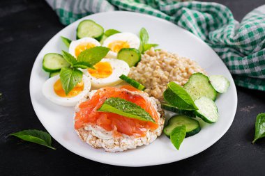 Kahvaltı yulaf lapası haşlanmış yumurta, somon sandviçi ve salatalık salatası. Sağlıklı yiyecekler. Öğle yemeği..