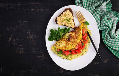 Kahvaltıda. Kabaklı omlet, peynir ve domates salatası ve beyaz tabakta sandviç. Frittata - İtalyan omleti. Üst manzara, düz uzanma