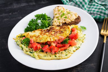 Kahvaltıda. Kabaklı omlet, peynir ve domates salatası ve beyaz tabakta sandviç. Frittata - İtalyan omleti.