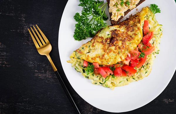 Kahvaltıda. Kabaklı omlet, peynir ve domates salatası ve beyaz tabakta sandviç. Frittata - İtalyan omleti. Üst manzara, düz uzanma