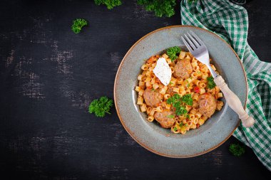 Domates soslu köfteli İtalyan geleneksel ditalini makarna ve kasede sebze. Domates soslu Ditalini makarna ve biftek topları. Üst Manzara. Düz yatıyordu.