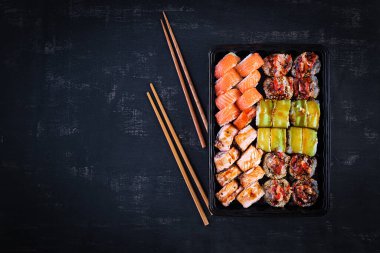 Asya yemeği seti. Sushi, siyah bir arkaplanda yuvarlanıyor. Üst manzara, yukarıda.