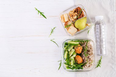 Beslenme çantası yulaf ezmesi, salatalık salatası, ve fındık, ekmek, beyaz ahşap arka planda armut. Beslenme çantası yemeği. Üst manzara, düz uzanma